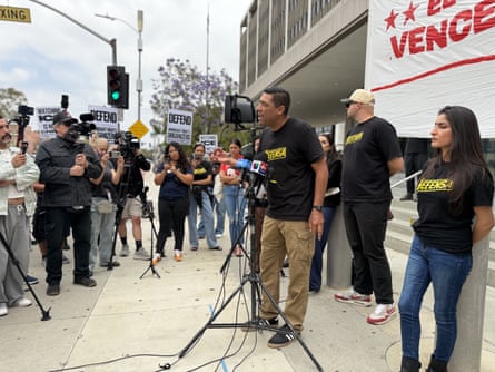Aa man speaking into microphones in front of a large crowd.