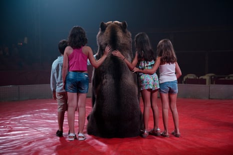 A brown bear poses for a photo with children at a circus, Spain