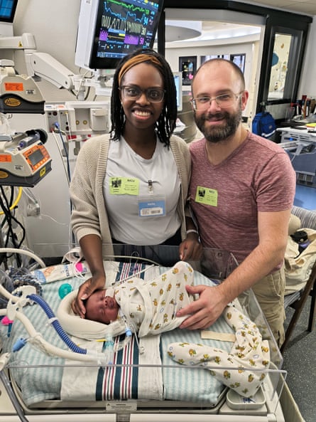a mother and father smile with their newborn child