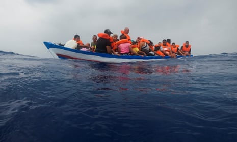 Migrants on a wooden boat wait for the Italian Guardia Costiera in the Mediterranean