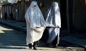 Afghan burqa-clad women walk along a road in Kandahar