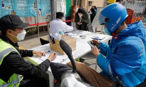 A food delivery man scans the code on a mobile phone to show the green code as he prepares to enter into 798 Art Zone in Beijing.