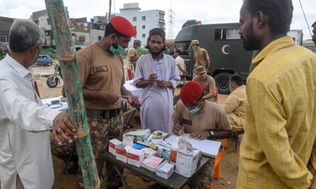 An army medical team providing treatment to flood-affected people at a camp.