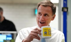 Britain's Chancellor Jeremy Hunt has drink and biscuits with employees during a visit to a builders warehouse in London yesterday