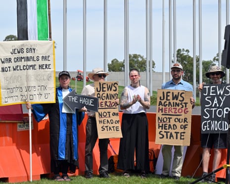 Protesters hold up signs at a rally to protest against the visit of Israeli president Isaac Herzog