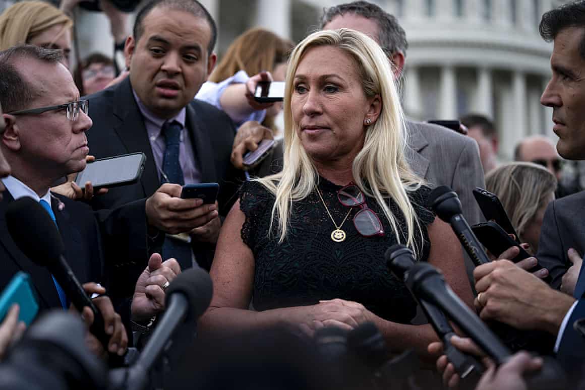 Majorie Taylor Greene surrounded by people with microphones.