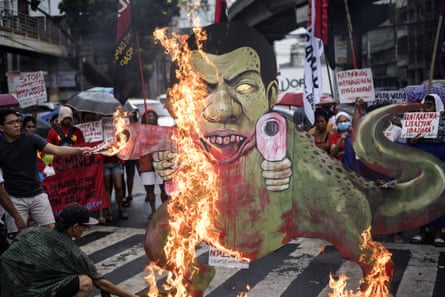 Activists burn a caricature of Philippine president Rodrigo Duterte as a gun-toting dinosaur.