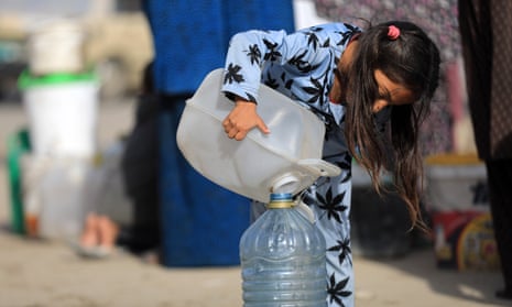 A girl refills a water bottle in Gaza