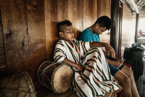 Two teenage boys – boy on left is in traditional dress; boy on right wears a T-shirt and is looking at his phone