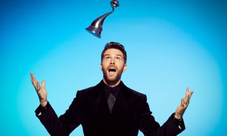 Joel Dommett throwing a National Television Award above his head