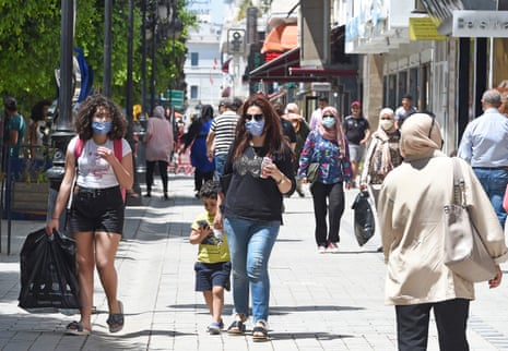 Women wearing protective face masks walk in the Tunisian capital, Tunis, on Tuesday