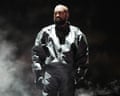 Kanye West on stage dressed in a black jacket and black gloves