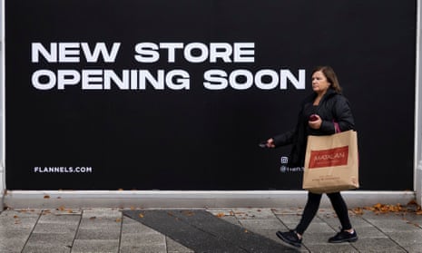 A woman passes a sign saying new Flannels store opening soon in Cardiff, Wales.