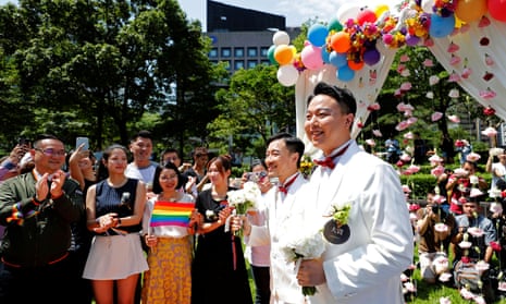 Newlyweds walk on a giant rainbow flag at a pro same-sex marriage party after registering their marriage in Taipei.