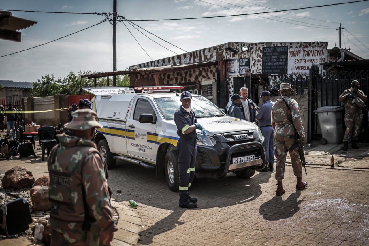 Members of South Africa’s forensic pathology service and armed forces personnel inspect the scene of the shooting at the bar in Wedela.