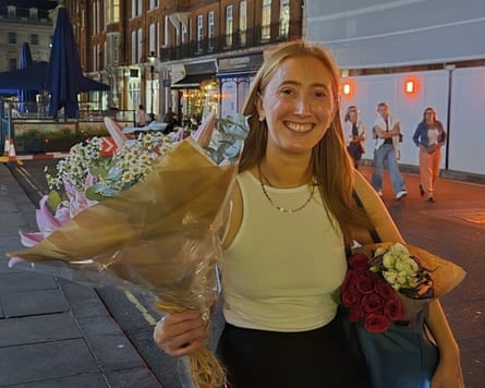 Chloe Moffat holding a bouquet of flowers in a street