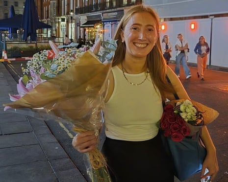 Chloe Moffat holding bouquets of flowers standing on a street at night