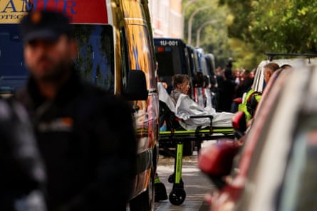 Abascal can be seen through a gap between vehicles, including police vans, as she is carried on a stretcher