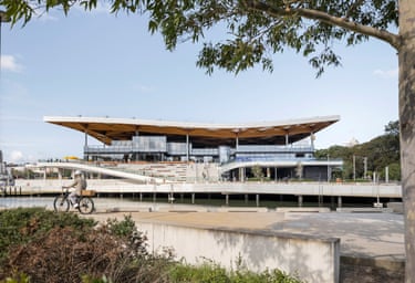 A cyclist rides past the New Sydney Fish Market’s curved roof beside the water
