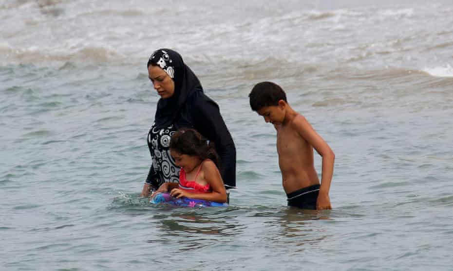 A Muslim woman enters the sea in a burkini.