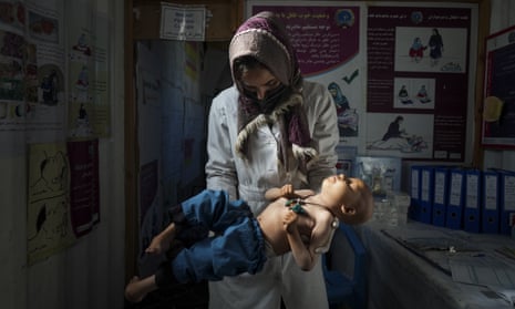 A nurse checks the weight of a child in a  settlement near Herat, Afghanistan, December 2021.