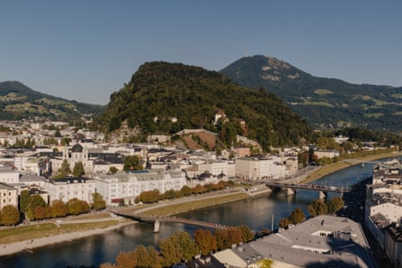 A view of a green hill seen across a river that is spanned by two bridges