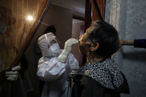 A medical worker takes a swab from an elderly resident to be tested for Covid-19 at her home in Wuhan on 14 May 2020.