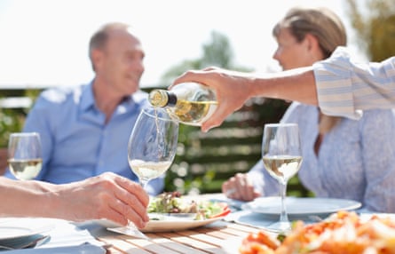 Man pouring wine at sunny table with friends