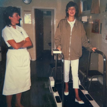 A woman walking on a treadmill with a nurse standing beside her
