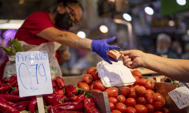 A customer pays for vegetables at the Maravillas market in Madrid