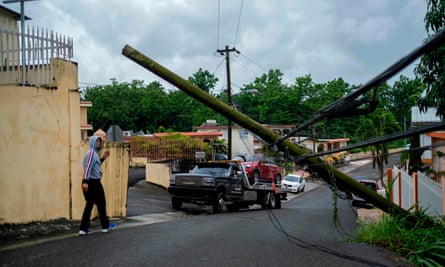 A man guides a tow truck under a downed power line pole after Tropical Storm Isaias affected the area in Mayaguez, Puerto Rico last week.