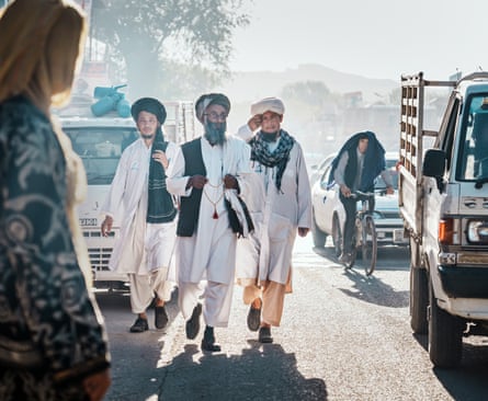 Three Afghan men patrol a street between traffic