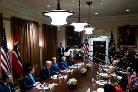 Donald Trump speaks while seated between advisers at a long table