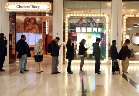 Seven people stand in line in a shopping centre