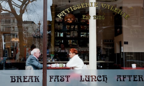 A couple seen through a large window as they dine at a Patisserie Valerie cafe in London