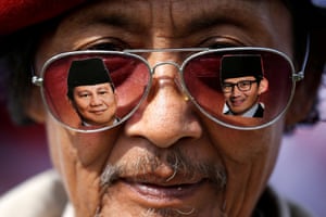 a mean wears glasses showing images of Prabowo and his running mate