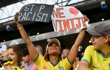 A Brazil supporter holds a sign reading” “Stop racism, we love Viní Jr”.