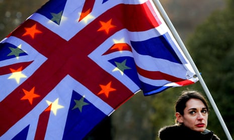 A protestor holds flags British and EU flags against the sunlight.