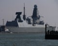HMS Duncan, a naval destroyer, sails past a pier as onlookers watch from Portsmouth