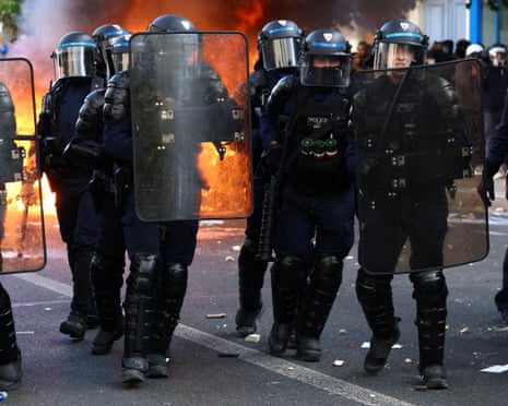 French CRS riot police stand in position near objects set on fire amid clashes with protesters in Paris.