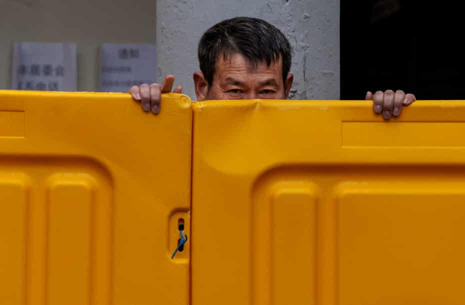 A man stands behind the fence in the compound under quarantine in Puxi.