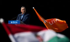 Viktor Orbán stands at a podium with the word 'Béke' (peace) on it, and flags waving below.