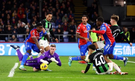 Crystal Palace's Dean Henderson saves an attempt while under pressure from Joao Pedro, Jack Henshilwood, and Brighton & Hove Albion's Facundo Buonanotti.