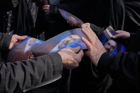 A close of two pairs of hands, one pair handing another a photo of Ayatollah Mojtaba Khamenei.