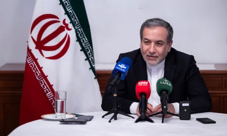 Seyed Abbas Araghchi sits at a table beside the Iranian flag