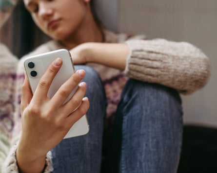 A girl crying looking at her phone