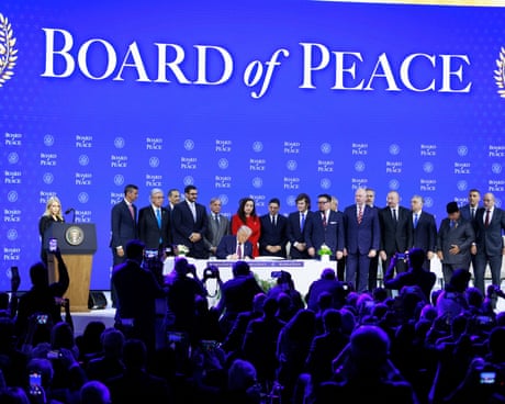 people stand around a man signing a document beneath a banner that reads board of peace