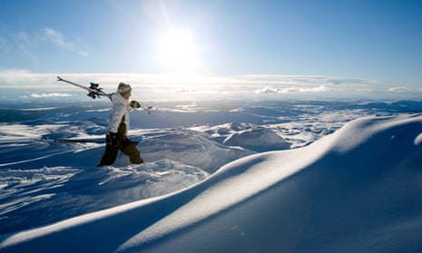 Skiing in Åre, the largest winter sports resort in Sweden. A man holding his skis on his shoulder walks through deep powder snow.