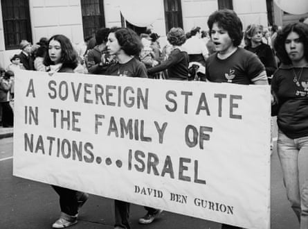 people hold a sign that reads ‘a sovereign state in the family of nations Israel; David Ben Gurion’