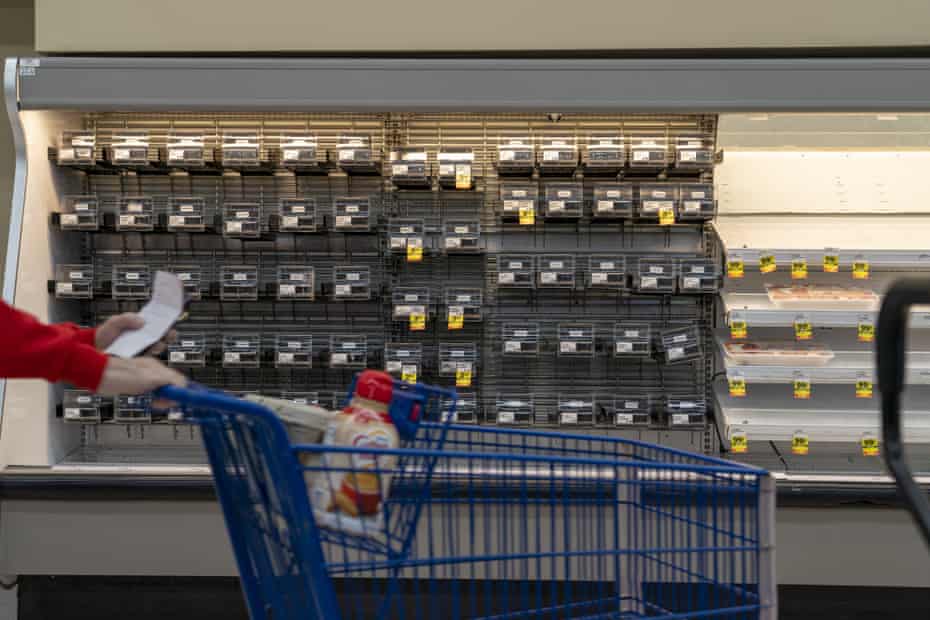 A customer pushes a shopping cart past empty shelves at a grocery store in Dayton, Ohio,